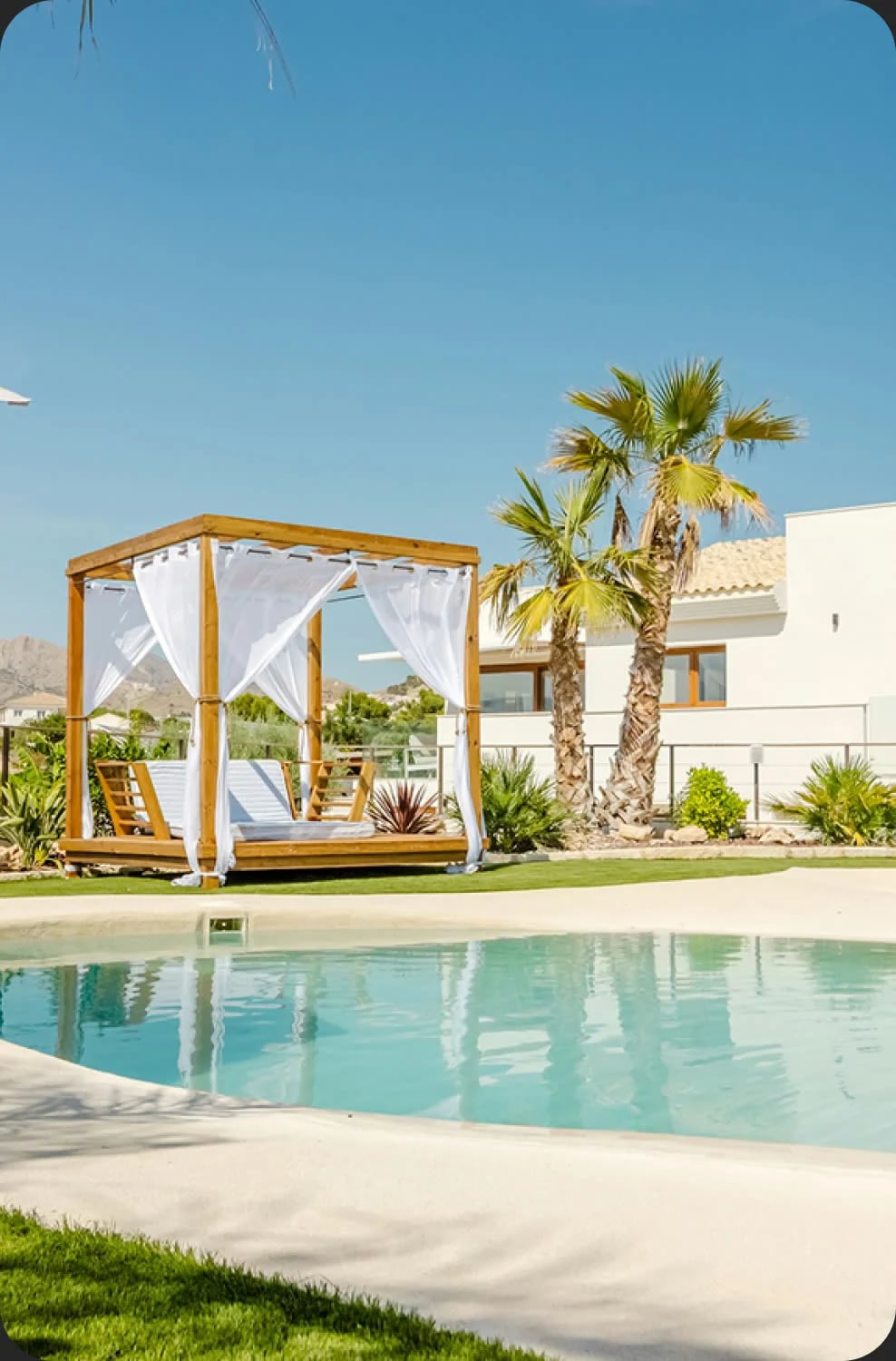 Salón abierto con tumbonas y cocina exterior junto a la piscina